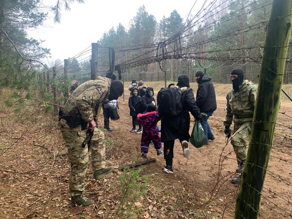 Мигранты перелазят через колючий забор на белорусско-польской границе - Sputnik Беларусь