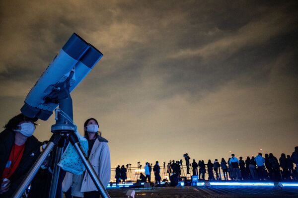 Люди наблюдают за ночным небом в телескоп со смотровой площадки Роппонги-Хиллз в Токио.Затмение можно назвать &quot;почти полным&quot; лунным затмением, так как почти вся Луна зайдет в тень Земли. Большая часть лунного диска приобрела красноватый оттенок. - Sputnik Беларусь