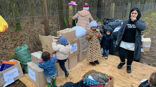 Мигранты выбирают одежду из гуманитарной помощи - Sputnik Беларусь