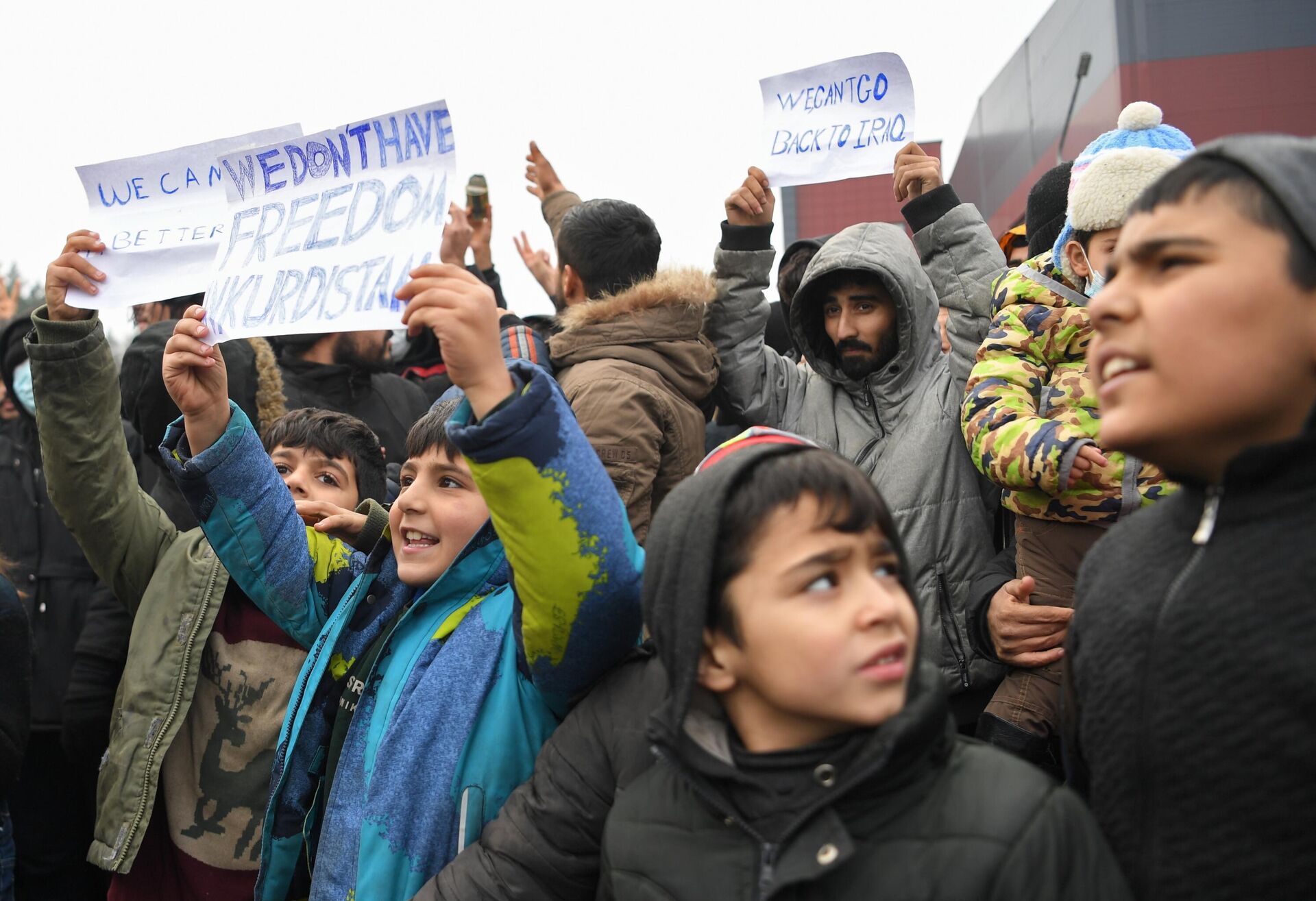Дети держат плакат Мы не будем свободными в Курдистане в центре временного содержания мигрантов - Sputnik Беларусь, 1920, 25.11.2021