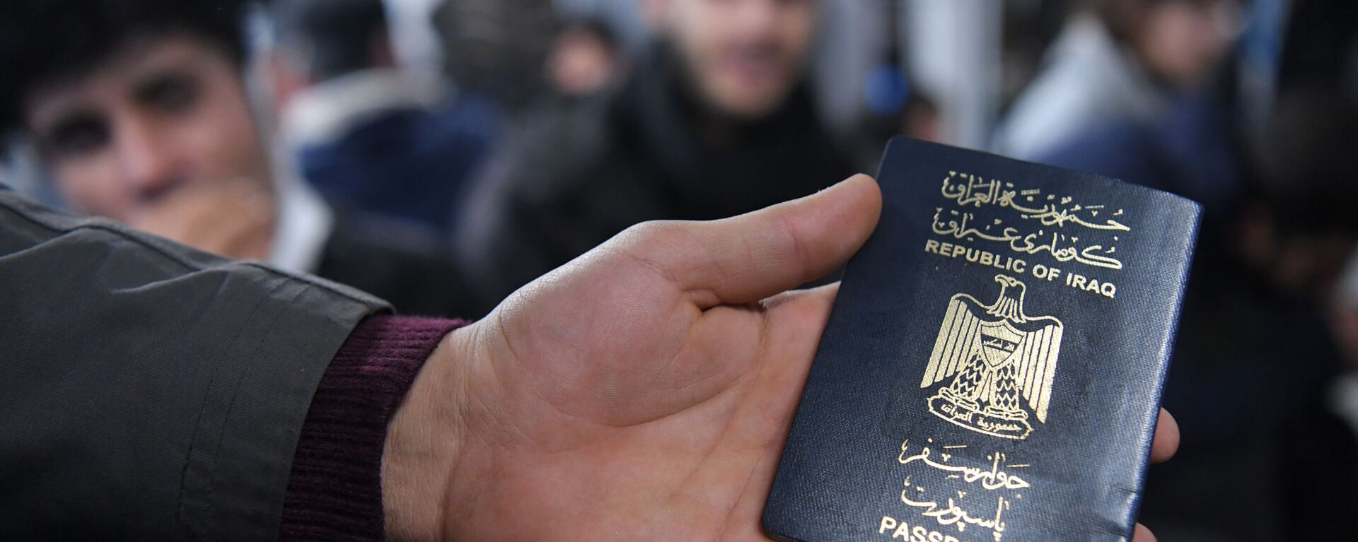 Иракский паспорт в руке одного из беженцев, ожидающих в международном аэропорту Минска вывозных рейсов авиакомпании Iraqi Airways - Sputnik Беларусь, 1920, 15.12.2021
