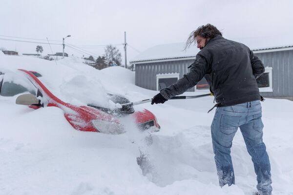 Житель Норвегии убирает снег со своей машины в Агдере. - Sputnik Беларусь