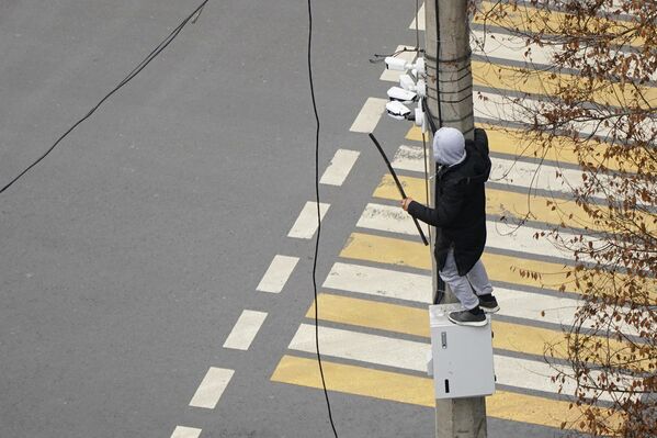 Демонстрант пытается демонтировать камеру видеонаблюдения на столбе во время акции протеста в Алматы. - Sputnik Беларусь