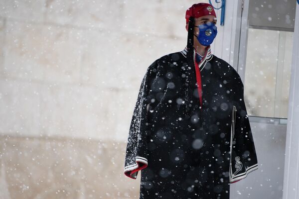 Сотрудник президентской гвардии Греции стоит у могилы Неизвестного солдата у здания греческого парламента во время снегопада. - Sputnik Беларусь