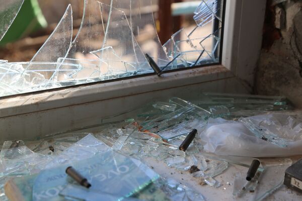 Разбитое окно и гильзы на подоконнике в жилом доме в Киевском районе Донецка - Sputnik Беларусь