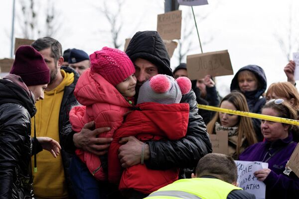 Мужчина обнимает своих дочерей после того, как они прибыли в Польшу из Украины. - Sputnik Беларусь