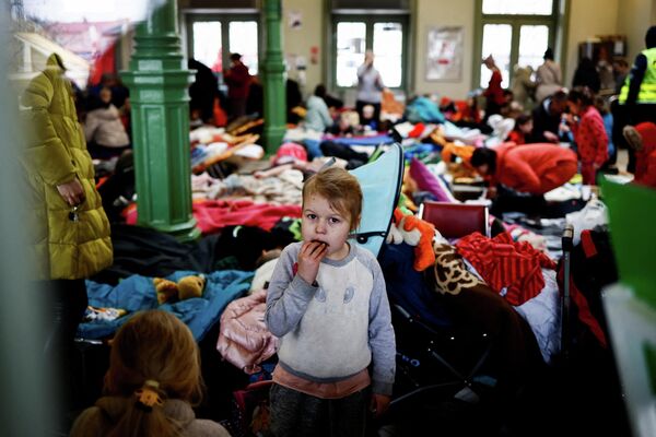 Ребенок ест печенье во временном приюте для беженцев на вокзале в Перемышле. - Sputnik Беларусь
