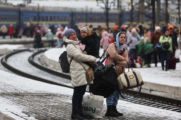 Украинские семьи ждут поезда, направляющегося в Польшу, на вокзале во Львове.Более 1,4 млн беженцев прибыли в Польшу с Украины с 24 февраля. - Sputnik Беларусь