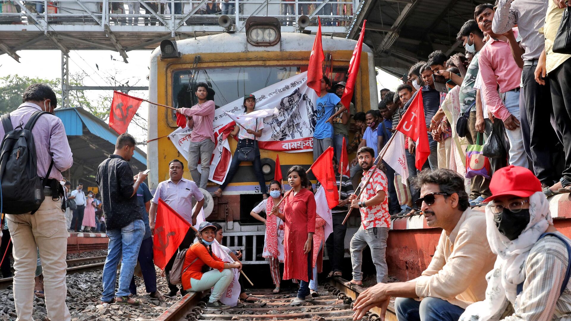 Демонстранты блокируют пассажирский поезд во время двухдневной забастовки в знак протеста против так называемой антинародной политики центрального правительства в Калькутте, Индия, 28 марта 2022 года - Sputnik Беларусь, 1920, 28.03.2022