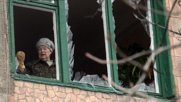 Женщина убирает осколки оконных стекол в жилом доме в Горловке, поврежденном в результате обстрела - Sputnik Беларусь