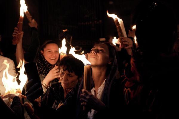 Христианские паломники держат свечи, собравшись во время церемонии сошествия Благодатного огня в храме Гроба Господня в Иерусалиме, 23 апреля 2022 года. - Sputnik Беларусь