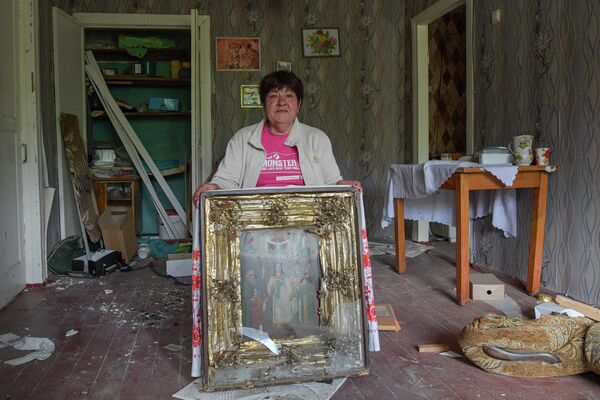 Женщина показывает поврежденную при обстрелах семейную икону в своем разрушенном доме в городе Попасная - Sputnik Беларусь