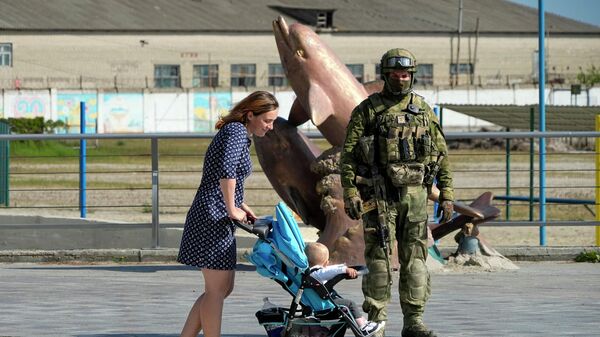 Женщина с коляской на набережной Херсона рядом с российским военным - Sputnik Беларусь
