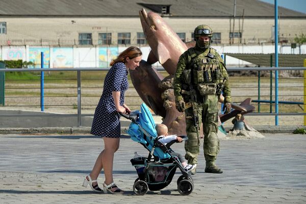 Женщина с коляской на набережной Херсона рядом с российским военным. - Sputnik Беларусь