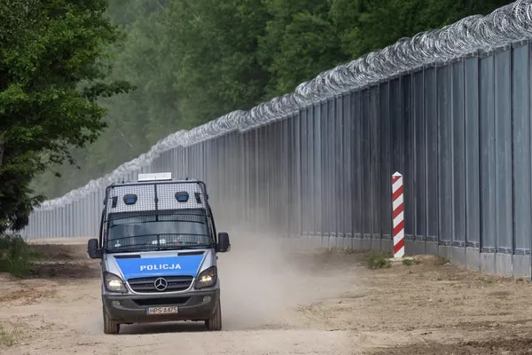 Полицейская машина патрулирует дорогу вдоль стены на польско-белорусской границе. - Sputnik Беларусь