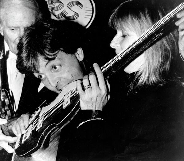 Пол Маккартни кусает торт в виде 4-струнной бас-гитары во время обеда в ресторане Claridge&#x27;s в Лондоне 20 декабря 1989 года. - Sputnik Беларусь