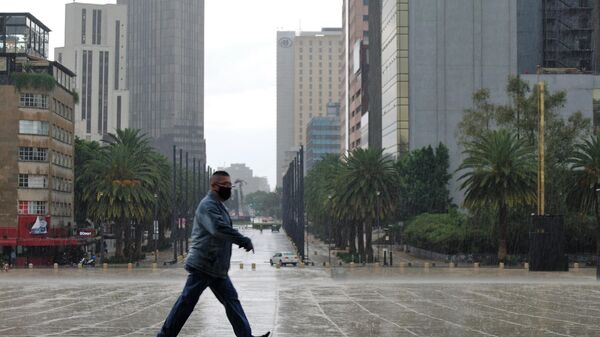 Мужчина идет под дождем по одной из улиц Мехико - Sputnik Беларусь
