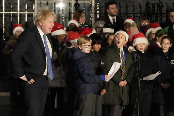 Премьер-министр Великобритании Борис Джонсон слушает пение детского хора во время церемонии включения огней рождественской елки на Даунинг-стрит в Лондоне, среда, 1 декабря 2021 года. - Sputnik Беларусь
