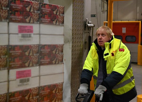 Премьер-министр Великобритании Борис Джонсон переносит поддон с шоколадным тортом в хранилище при температуре -25°C во время предвыборного визита в штаб-квартиру Iceland Foods в Дисайде, северо-восточный Уэльс, 8 ноября 2019 года. - Sputnik Беларусь