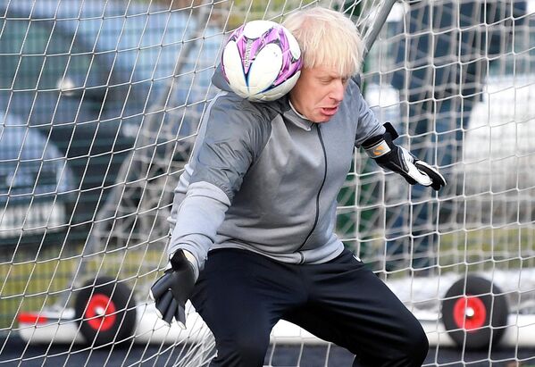 Премьер-министр Великобритании Борис Джонсон пытается отразить удар во время разминки перед футбольным матчем среди девочек во время предвыборной кампании в Чидл-Халме, на северо-западе Англии, 7 декабря 2019 года. - Sputnik Беларусь