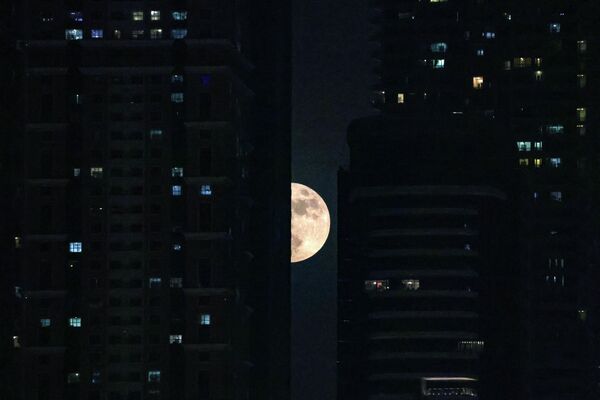 Луна выглядывает между домами на пристани Дубай Марина в эмирате Дубайского залива. - Sputnik Беларусь