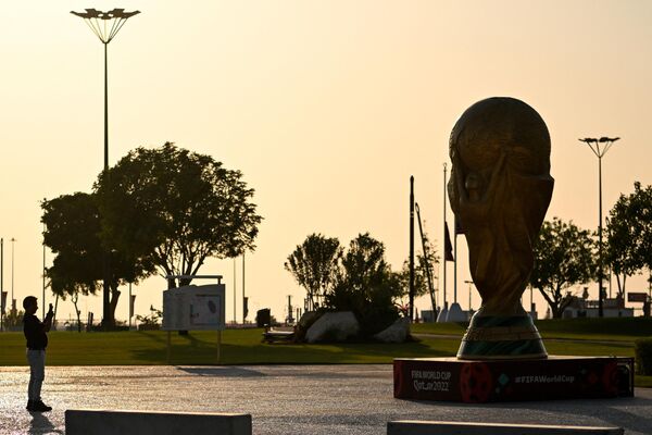 Мужчина фотографирует статую трофея чемпионата перед стадионом &quot;Аль-Байт&quot; в Аль-Хавре. - Sputnik Беларусь