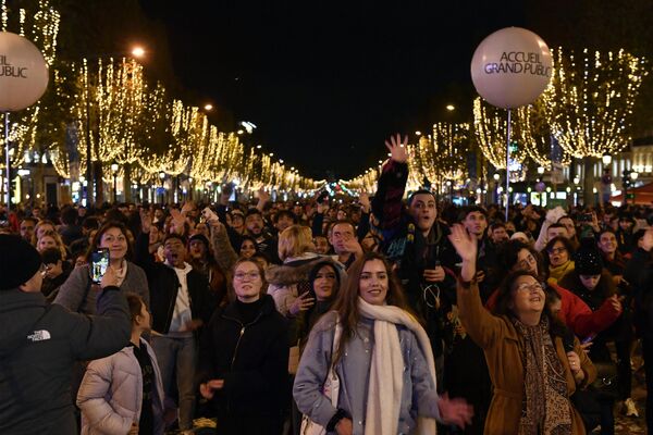 Люди присутствуют на включении рождественской иллюминации на Елисейских полях в Париже. - Sputnik Беларусь