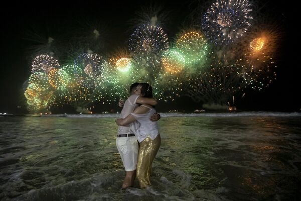 Люди празднуют начало Нового года на фоне фейерверков над пляжем Копакабана в Рио-де-Жанейро, Бразилия, рано утром в воскресенье, 1 января 2023 года. - Sputnik Беларусь