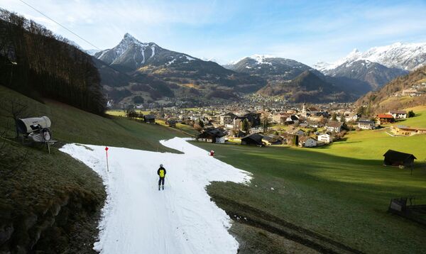 Лыжник спускается по искусственному горнолыжному склону среди зеленых холмов в Шрунсе, Австрия.Есть курорты, где открытыми для катания оставили только часть горнолыжных трасс. - Sputnik Беларусь