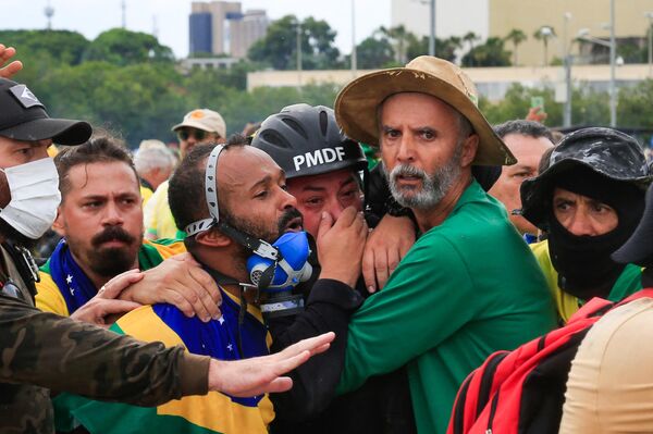 Сторонники бывшего президента Бразилии Жаира Болсонару удерживают офицера военной полиции во время столкновений - Sputnik Беларусь