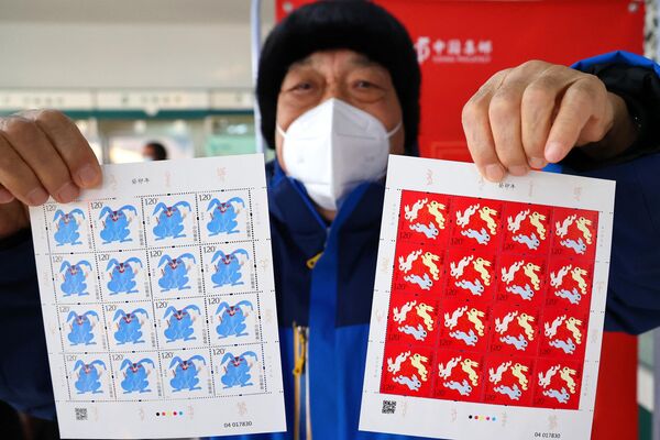 Мужчина показывает марки, посвященные Году Кролика, в почтовом отделении в Ляньюньгане, восточная китайская провинция Цзянсу. - Sputnik Беларусь