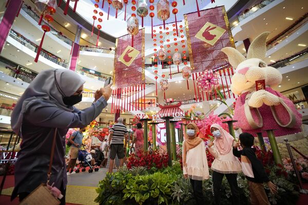 Женщина фотографирует своих детей на фоне новогодних украшений в торговом центре в Куала-Лумпуре. - Sputnik Беларусь