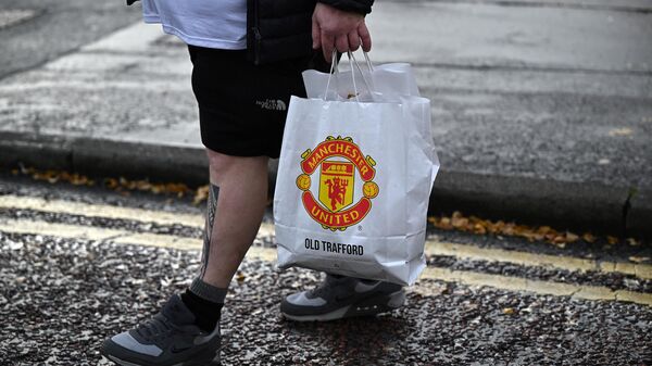 Болельщик с пакетом, на котором изображен логотип ФК Манчестер Юнайтед - Sputnik Беларусь