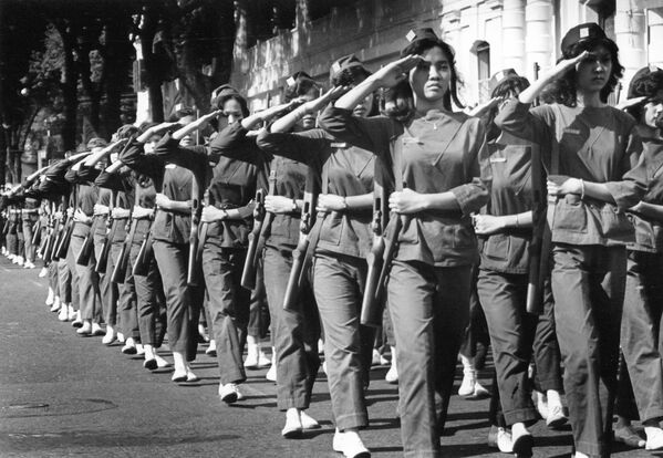 Вооруженные американскими винтовками женщины-военнослужащие салютуют маршем мимо первой леди Южного Вьетнама Мадам Ню во время выпускного в военном училище в Сайгоне, 27 февраля 1963 года. - Sputnik Беларусь