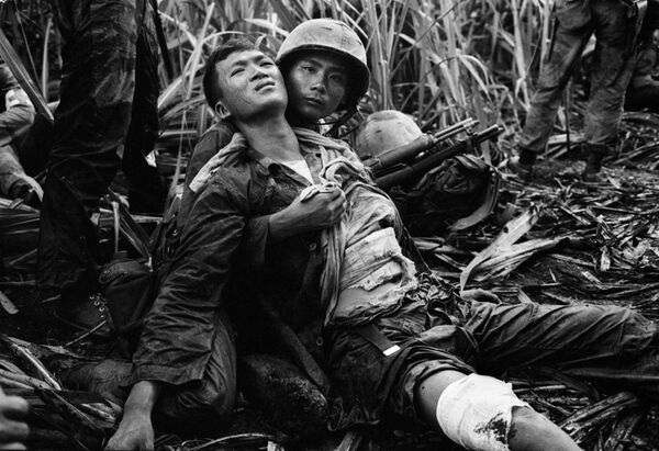 Южновьетнамский морской пехотинец, тяжело раненный в засаде Вьетконга, рядом с товарищем на поле сахарного тростника в Дык Хоа недалеко от Сайгона, 5 августа 1963 года. - Sputnik Беларусь