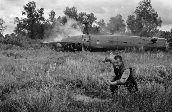 Американский летчик убегает от разбившегося военного вертолета CH-21 Shawnee возле деревни Камау Южного Вьетнама, 11 декабря 1962 года. - Sputnik Беларусь