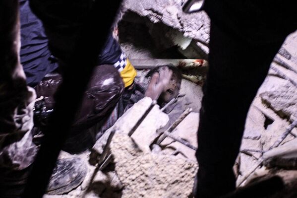 Спасатели пытаются освободить маленького мальчика из-под обломков рухнувшего после землетрясения здания в сирийском приграничном городе Азаз на удерживаемом боевиками севере провинции Алеппо рано утром 6 февраля 2023 года. - Sputnik Беларусь