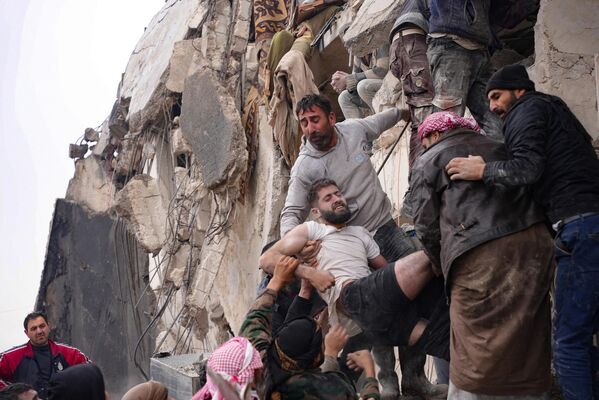 Жители извлекают раненого из-под обломков разрушенного здания после землетрясения в городе Джандарис, в сельской местности города Африн на северо-западе Сирии. - Sputnik Беларусь