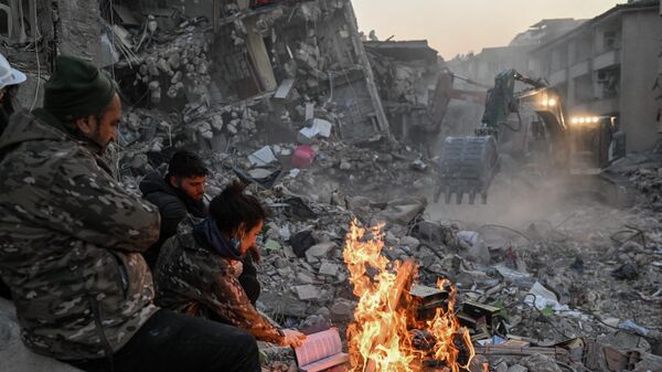 Местные жители сжигают книги, чтобы согреться, ожидая, пока их родственников вытащат из-под обломков разрушенных зданий в Хатае, 14 февраля 2023 года - Sputnik Беларусь
