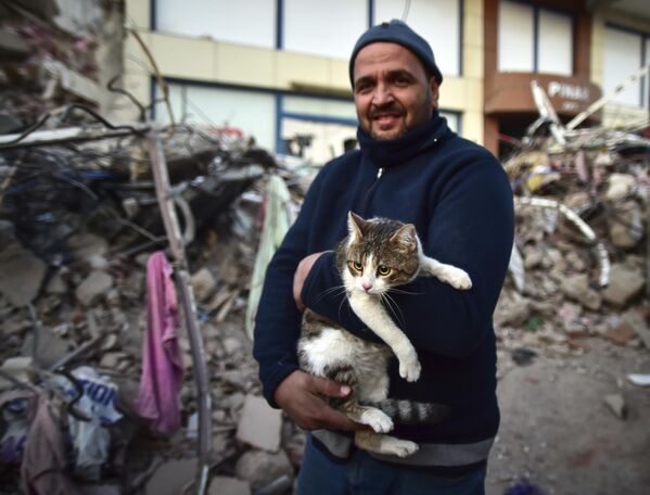 Мужчина держит свою кошку, спасенную из рухнувшего здания в Кахраманмараше. - Sputnik Беларусь