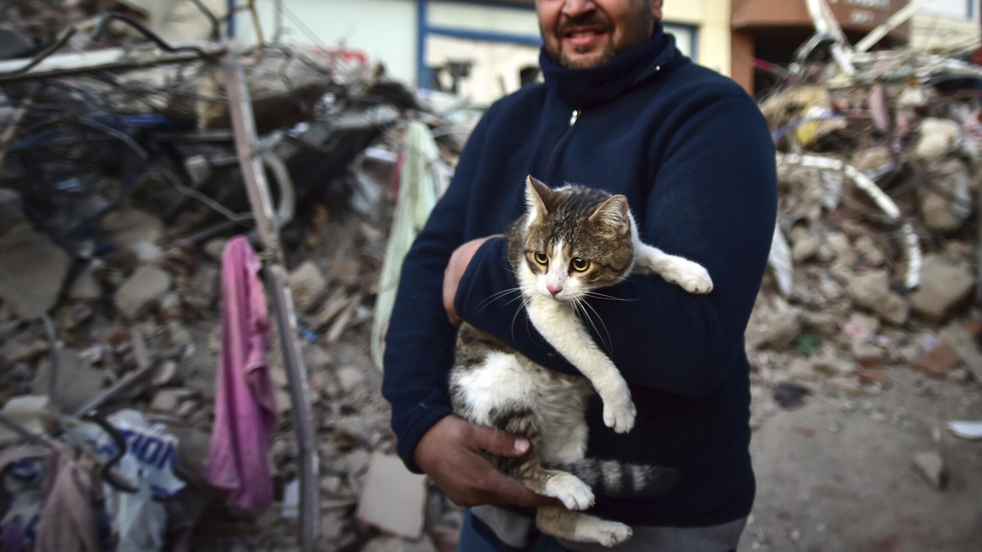 Мужчина держит на руках свою кошку, спасенную из рухнувшего здания, Турция - Sputnik Беларусь, 1920, 12.03.2023