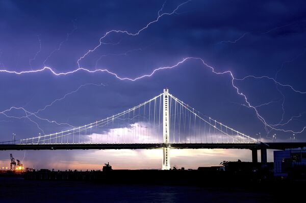 Молнии вспыхивают над мостом Сан-Франциско-Окленд через залив, штат Калифорния, 16 августа 2020 года. Многочисленные их удары вызвали тогда лесные пожары по всему региону. - Sputnik Беларусь