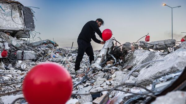 38-летний Огун Север Оур вешает воздушный шар на обломки рухнувшего здания в Антакье, южная Турция - Sputnik Беларусь