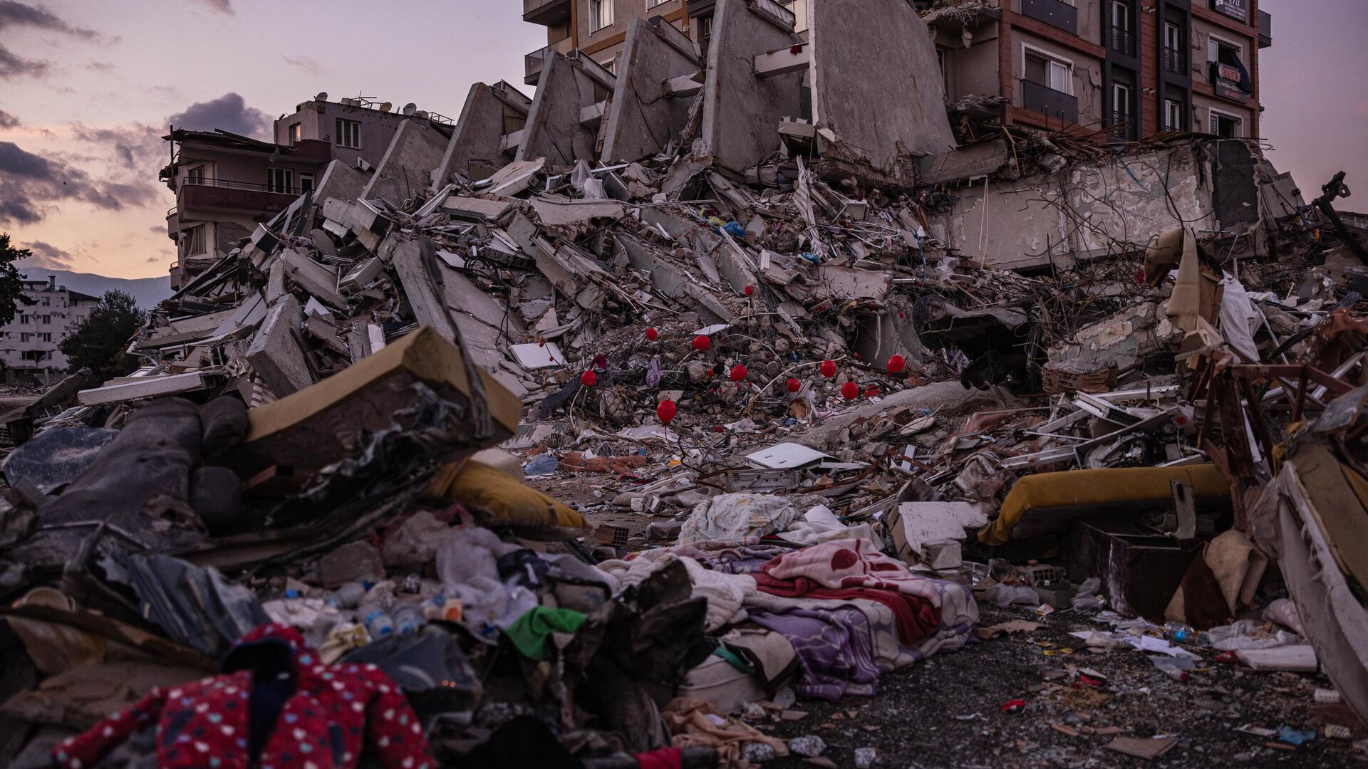 Красные воздушные шары, висящие на обломках рухнувших зданий как символ последних игрушек детей, погибших во время землетрясения в турецком городе Антакья - Sputnik Беларусь, 1920, 05.03.2023