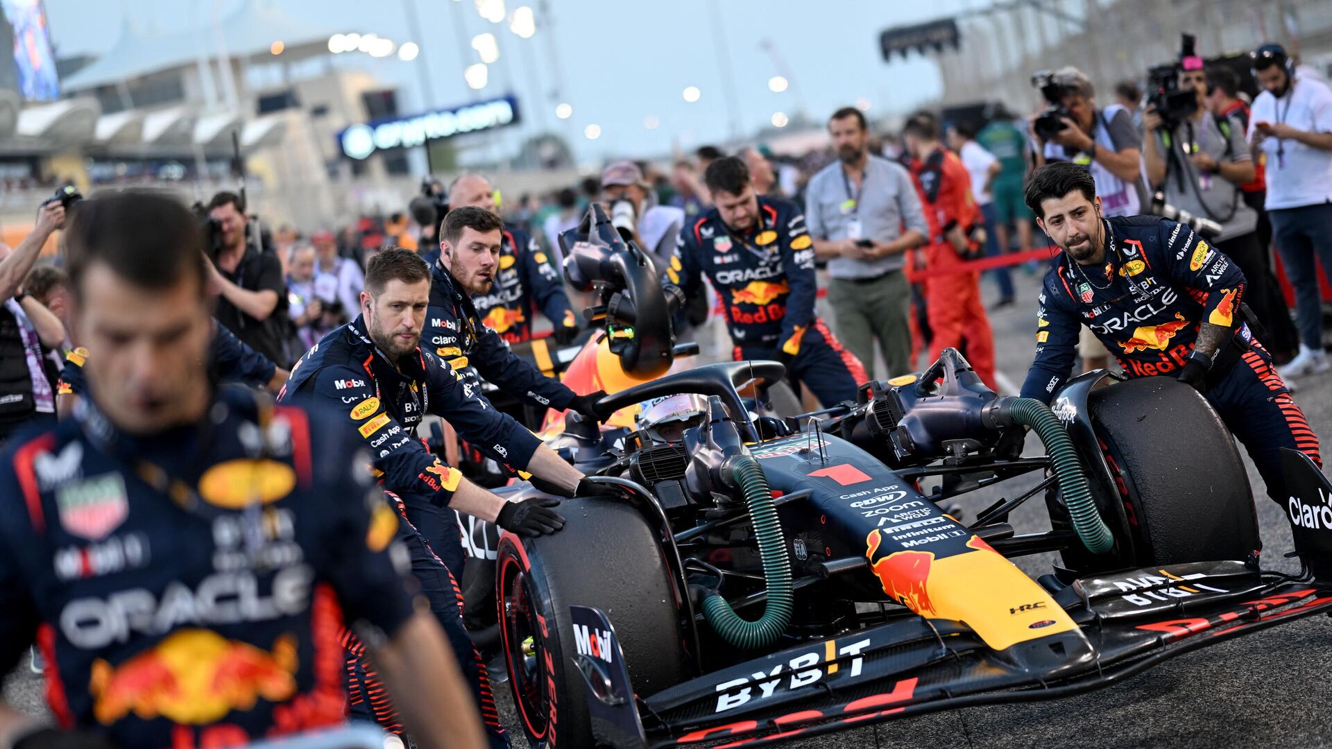 Механики толкают машину голландского гонщика Red Bull Racing Макса Ферстаппена перед стартом Гран-при Бахрейна Формулы-1 на международной трассе Бахрейна в Сахире 5 марта 2023 года - Sputnik Беларусь, 1920, 05.03.2023