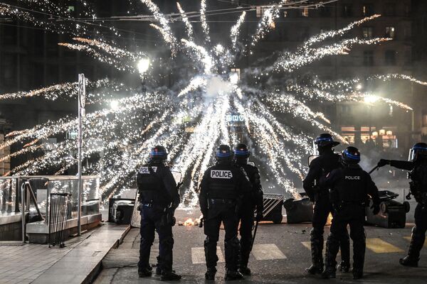 Полицейские стоят перед фейерверком, запущенным протестующими во время демонстрации в Лионе. - Sputnik Беларусь