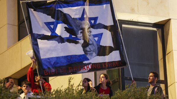 Израильские протестующие поднимают транспарант с изображением премьер-министра Биньямина Нетаньяху во время митинга против законопроекта о пересмотре судебной системы в Тель-Авиве, 25 марта 2023 года. - Sputnik Беларусь