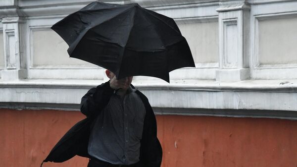 Мужчина идет под зонтом по улице  - Sputnik Беларусь