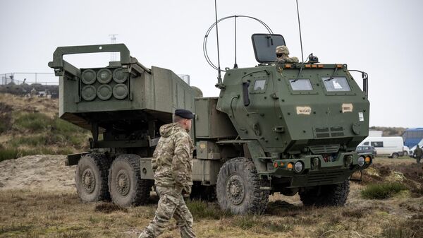 Военный возле высокомобильной артиллерийской ракетной системы M142 HIMARS - Sputnik Беларусь