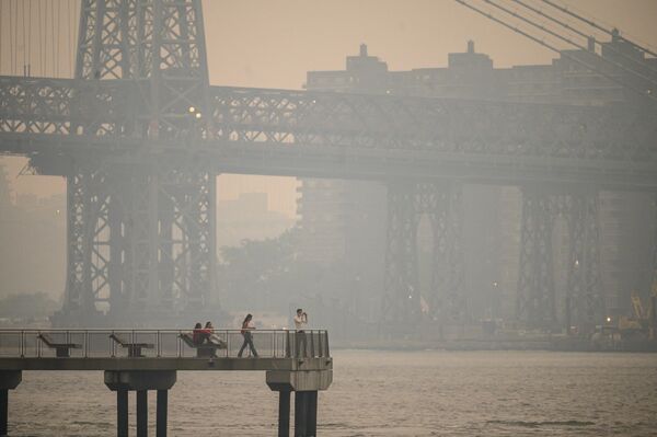 Люди стоят на пирсе на фоне окутанного дымом Нью-Йорка и Ист-Ривер в Бруклине. - Sputnik Беларусь